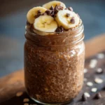 Chocolate Banana Overnight Oats in a mason jar topped with banana slices and chocolate chips